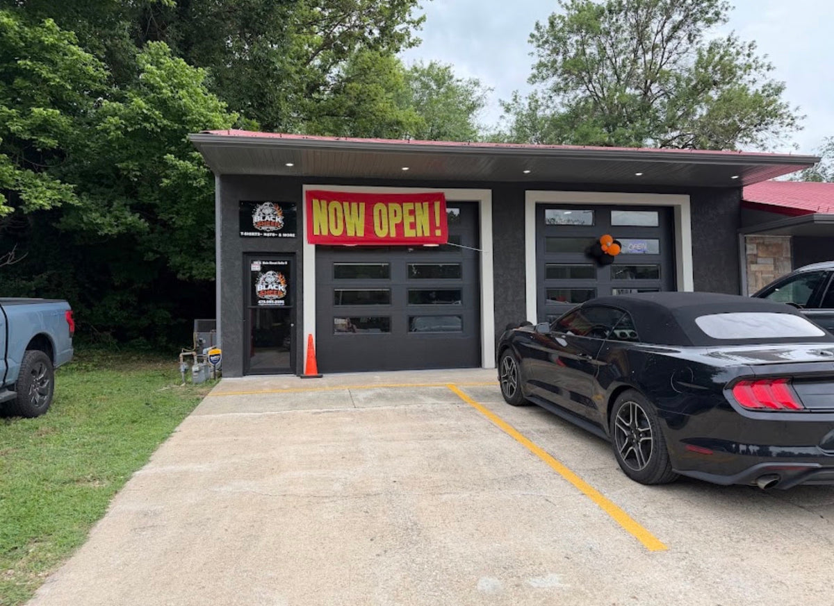 Black Sheep Custom Design storefront in Cave Springs, with the entrance, Black Sheep signs and Now Open banner.