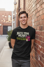 Model wearing a black Bless Your Heart graphic T-shirt outdoors beside a brick wall.